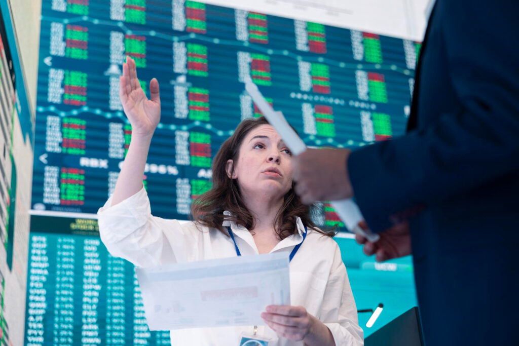 Binance AUD penalty: Woman gestures near stock market data, highlighting client classification issues.